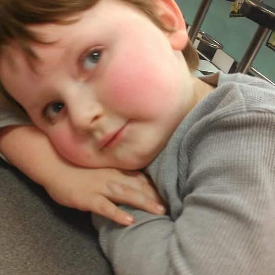 Photo of a young child in a diner. He’s resting his head on his hands on a table and looking upwards